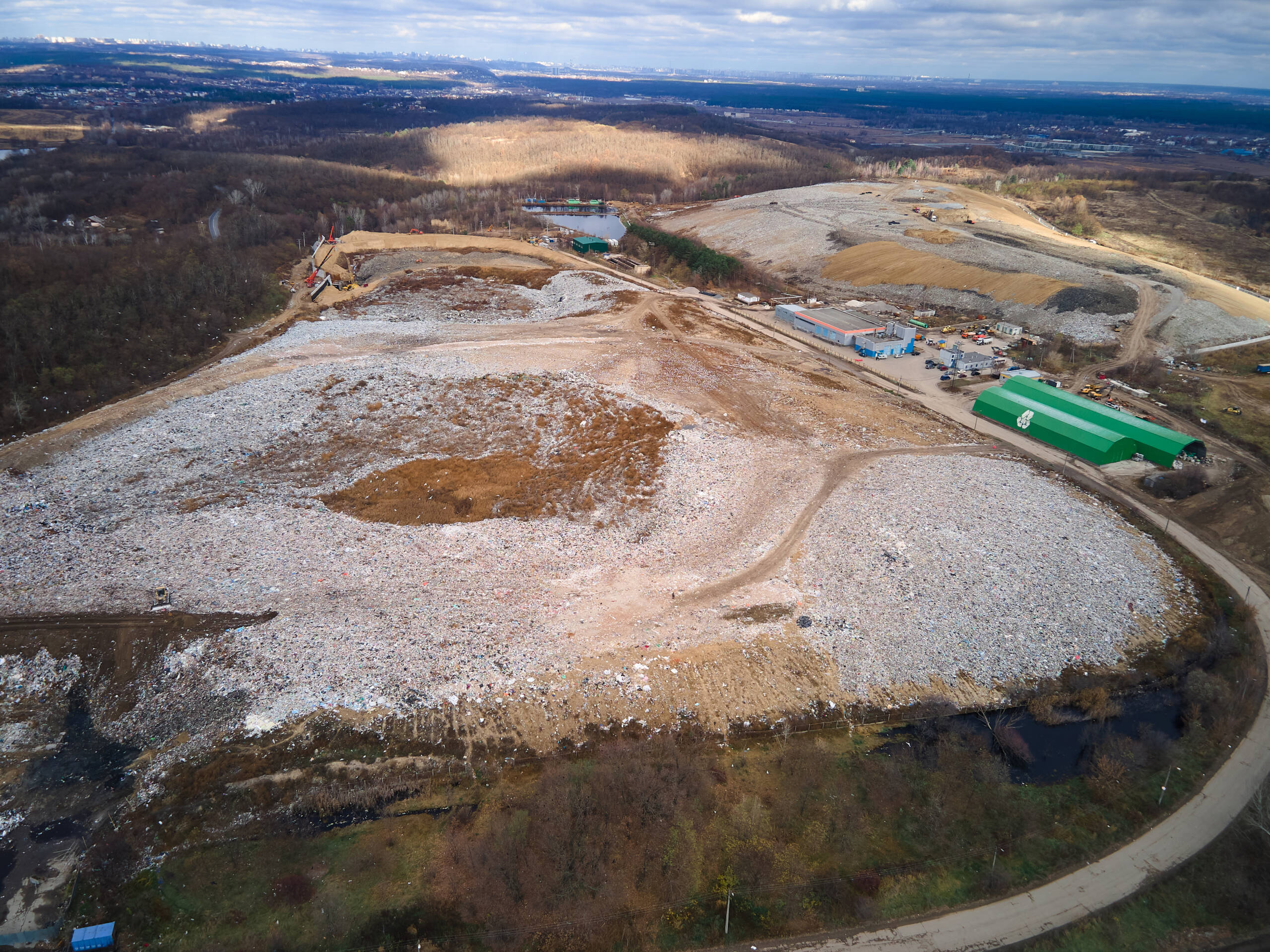 Aerial drone view of stack of different types of large mountain garbage pile, gulls feeding on food waste fly over It, waste disposal in dumping site, industrial factory in environmental pollution